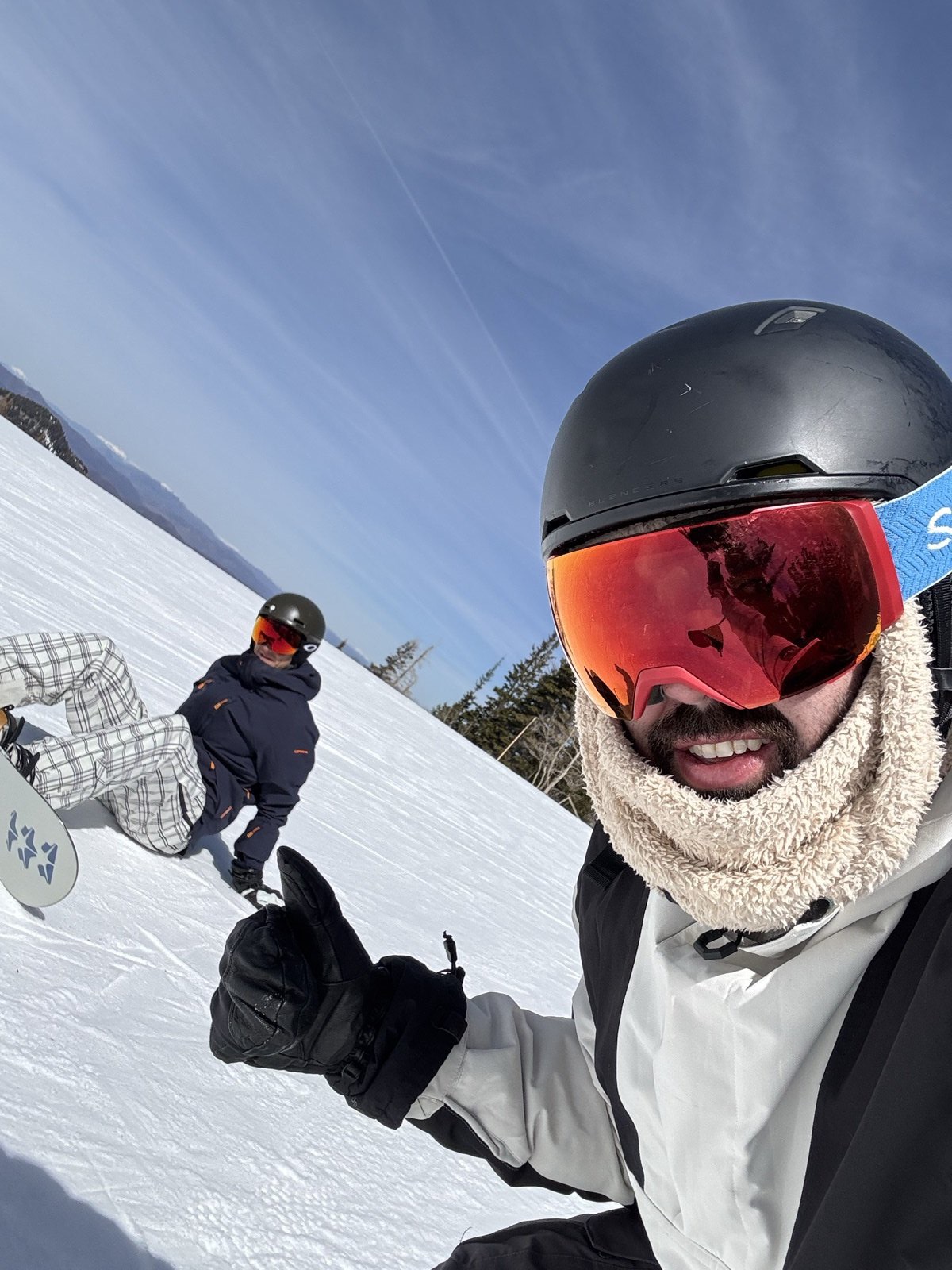 Michael giving a thumbs up at Park City with Andrew sitting in the snow behind him
